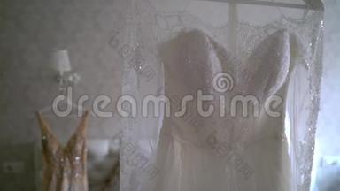 两件豪华婚纱挂在卧室里-白色和金色。 令人惊叹的新娘`<strong>蕾丝礼服</strong>的剪影